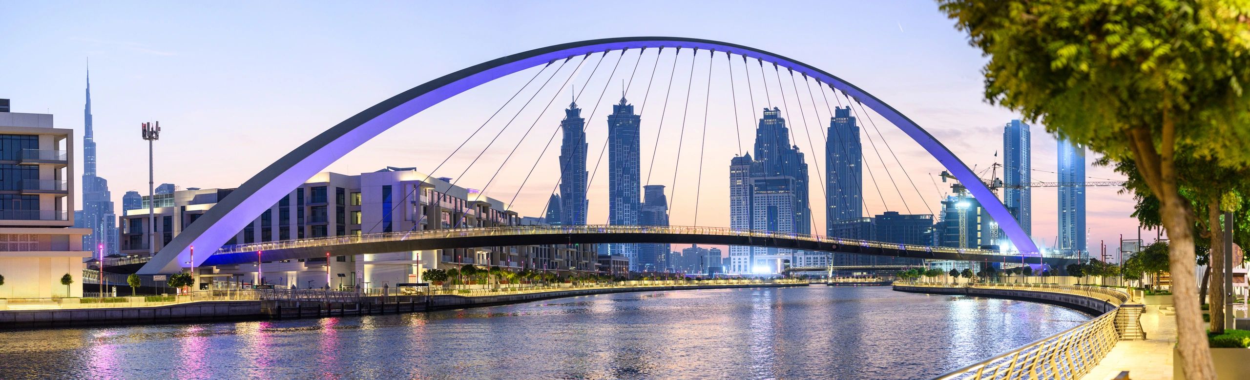 Panoramic view of Dubai Canal bridge and skyline at dawn
